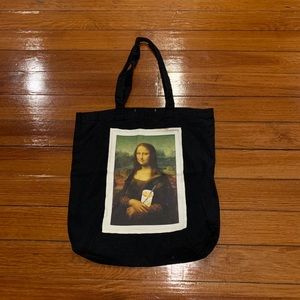 Black tote bag featuring Mona Lisa with reuseable straw